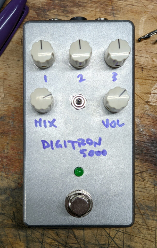 DIGITRON 5000, bare aluminum pedal with white knobs on workbench, closeup
