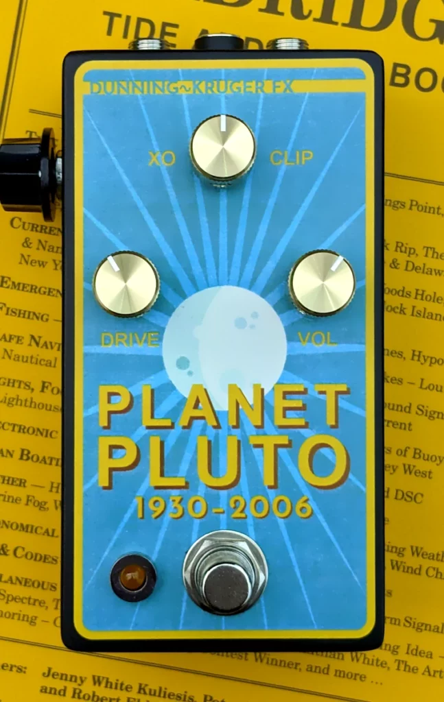 A blue and yellow guitar effect pedal on a copy of an Eldrdge Time and Pilot book 