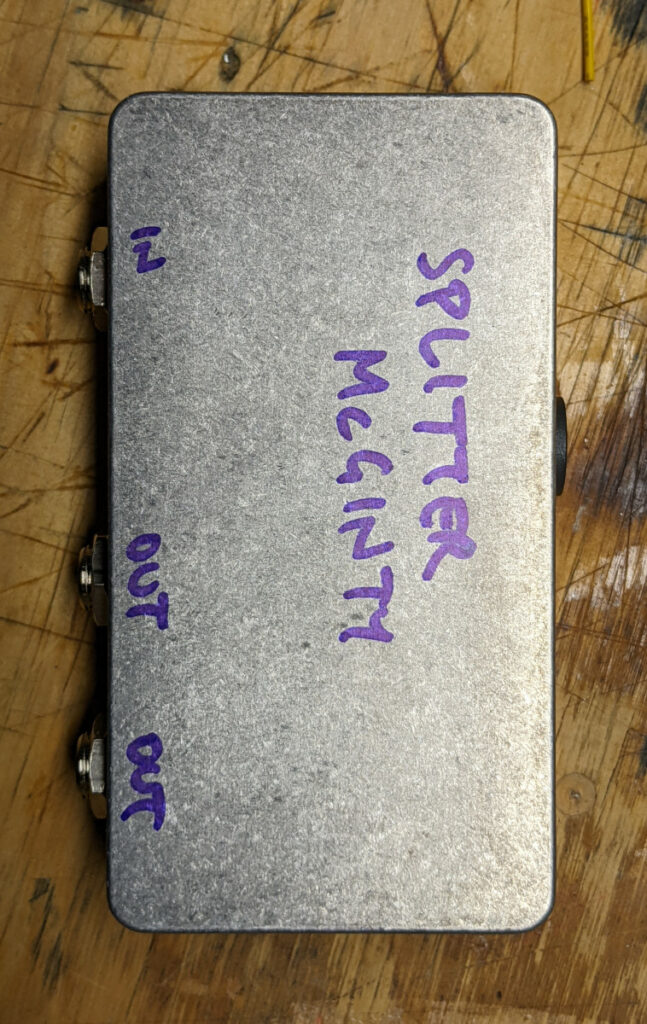 Unadorned bare aluminum pedal case with "Splitter McGinty" written on it in purple Sharpie.