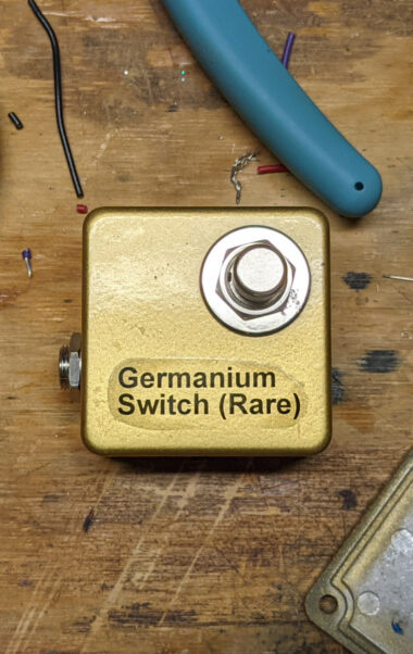 The Germanium Switch (Rare), a tiny pedal that looks like a gold ingot with Helvetica text and a single footswitch