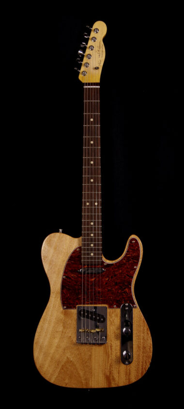 The Coronacaster guitar, slightly aged looking wood with a red tortoise shell pickguard, kind of like Prince's Hohner Mad Cat