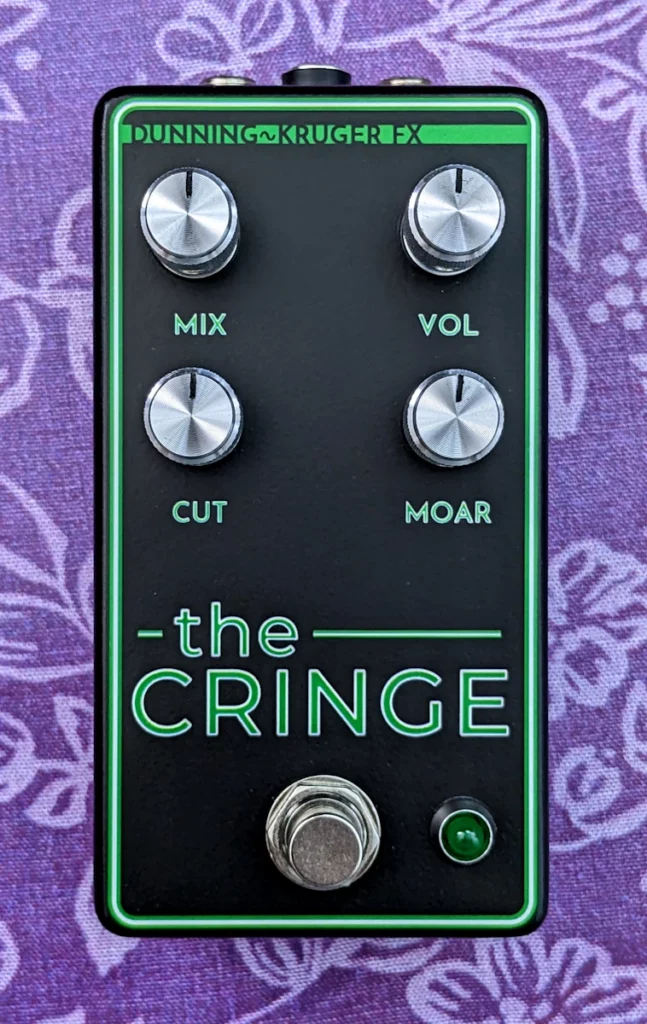 A black pedal with The Cringe written in green writing and silver knobs labeled Mix, Vol, Cut, Moar